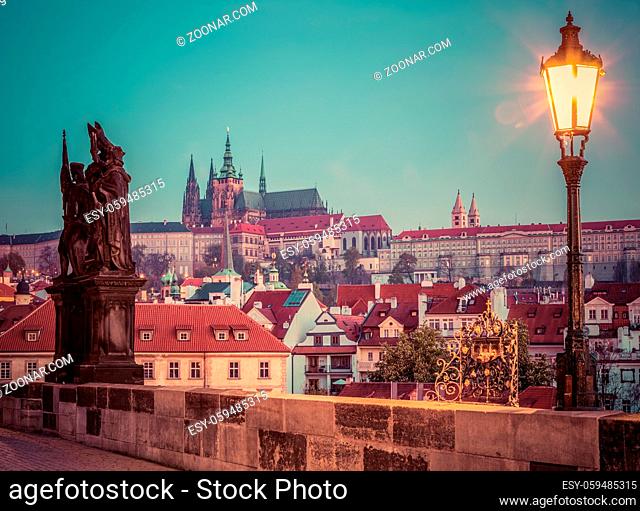 Charles Bridge at sunrise, Prague, Czech Republic. Dramatic statue and view on Prague Castle with St. Vitus Cathedral. Vintage