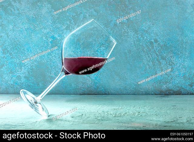A glass of red wine flying against a blue background with a place for text. A creative design template with copy space