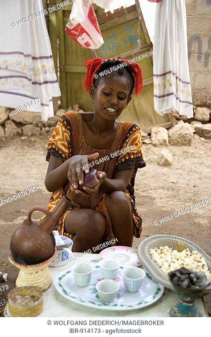 Young woman, 20-25 years old, putting frankincense on glowing charcoal for a pleasant aroma during a coffee ceremony in the open air, Red Sea, Massawa, Eritrea