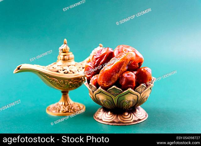 Ramadan, Dates in golden bowl, arabian Aladdin golden lamp vintage style on black green background