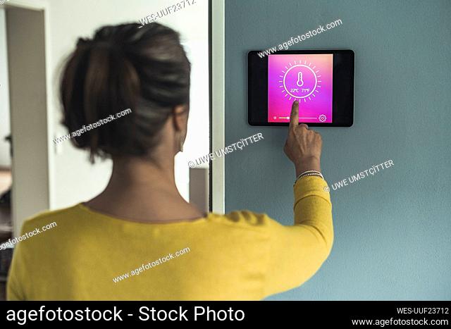 Woman using home automation device on wall