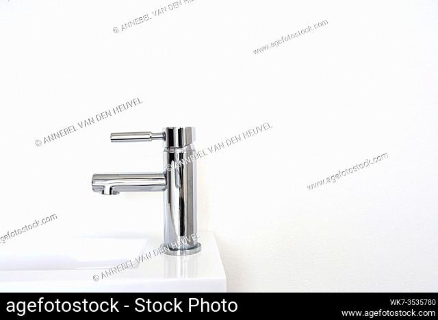 Silver metal faucet on white wall, new clean modern sink background minimalism