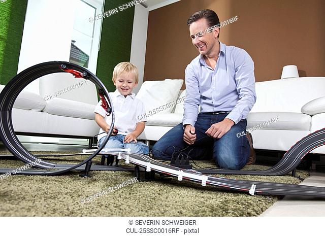 Father and son playing with race track