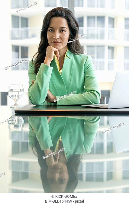 Hispanic businesswoman sitting at conference table