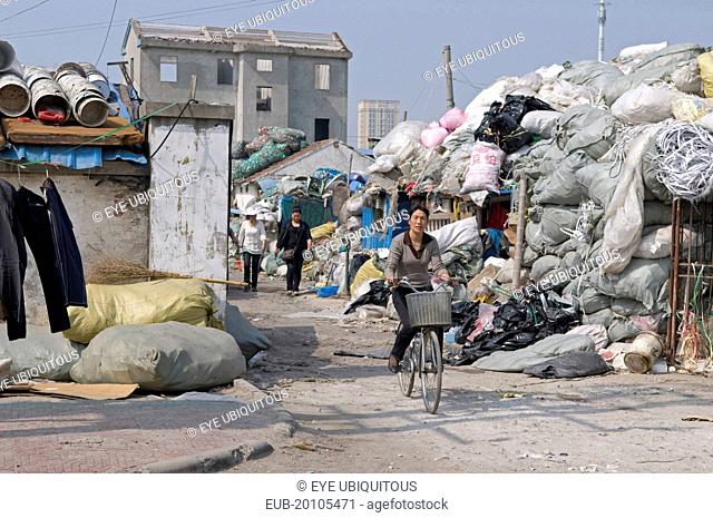 Female workers one on a bicycle leaving a recycling depot bundles of waste paper in plastic and polypropylene sacks