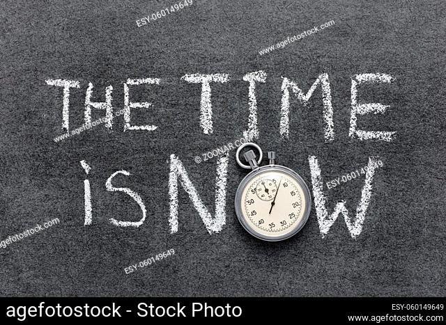 the time is now phrase handwritten on chalkboard with vintage precise stopwatch used instead of O