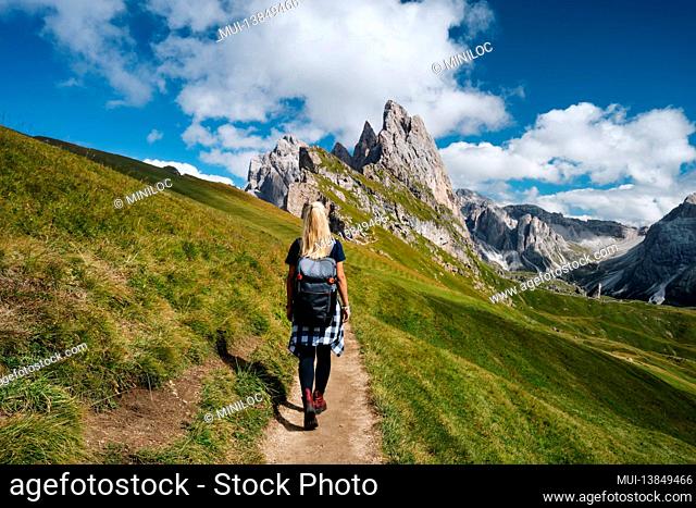 Women hiker on trail path and epic landscape of Seceda peak in Dolomites Alps, Odle mountain range, South Tyrol, Italy, Europe