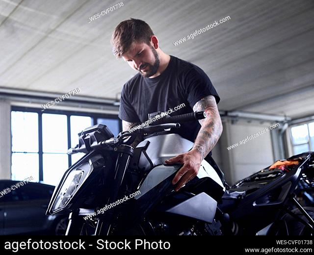 Technician checking motorcycle part at repair shop