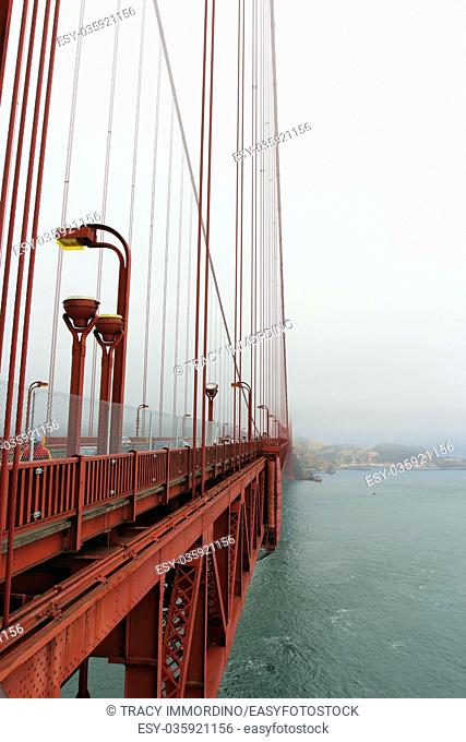 A view of the side of the Golden Gate Bridge, Marin County and the Pacific Ocean from a viewing area on the Golden Gate Bridge on a foggy, smog filled day