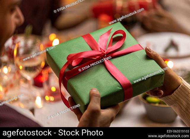 hands holding christmas gift at dinner party