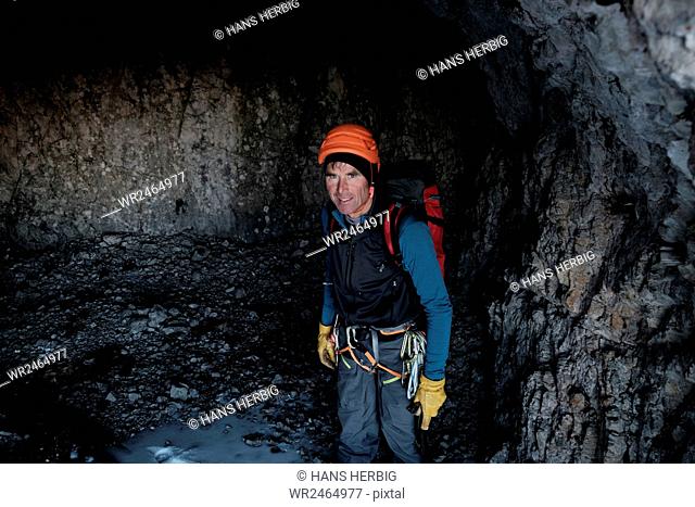 Mountain guide with helmet and backpack standing in cave