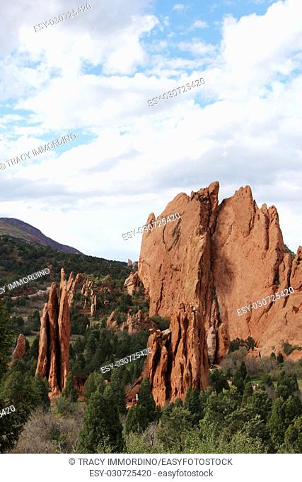 Sweeping landscape view of red rock pinnacles and unique rock formations with pine covered mountains in the background while hiking at the Garden of the Gods in...