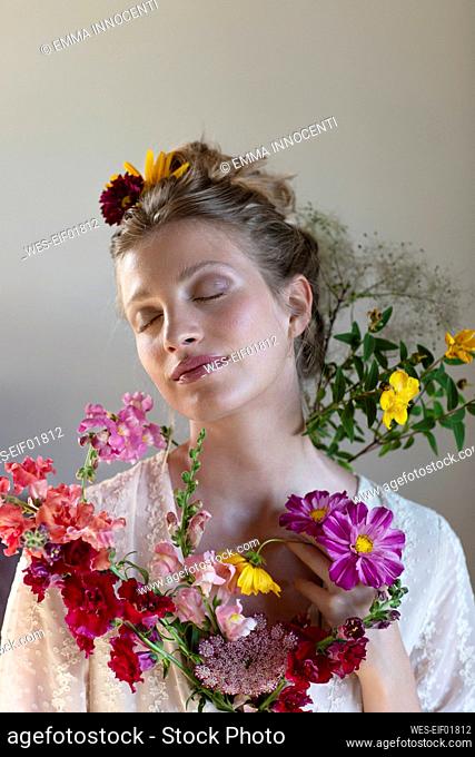 Young woman with multi colored wildflowers in front of white background