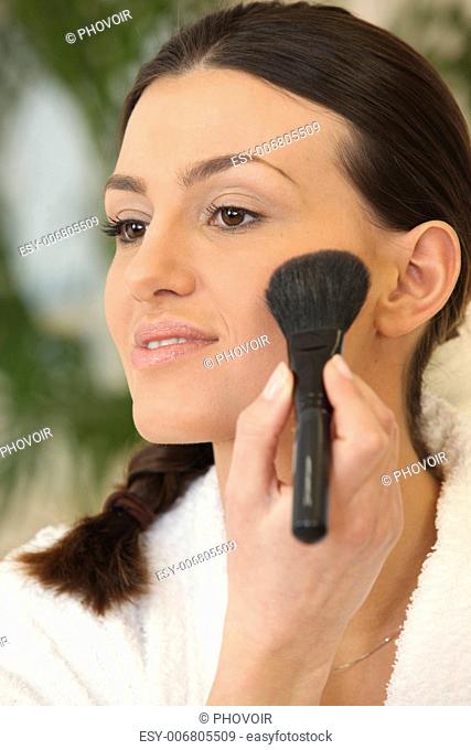 Woman applying blush on the cheek