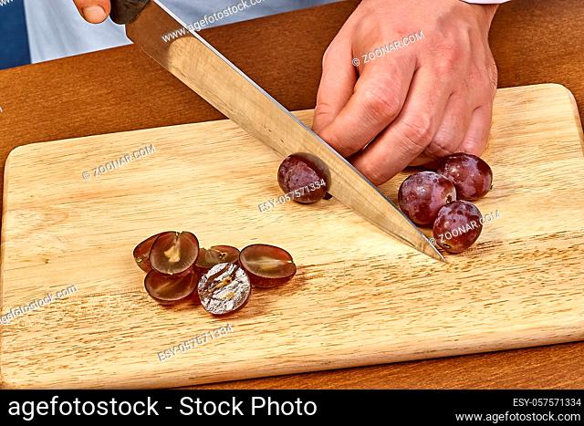 Chef-cook sliced grapes on a cutting board. Cutting ingredients closeup