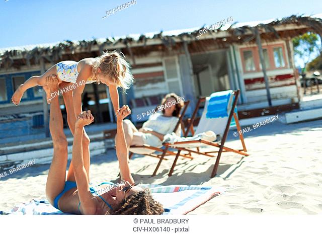 Playful mother and daughter on sunny beach
