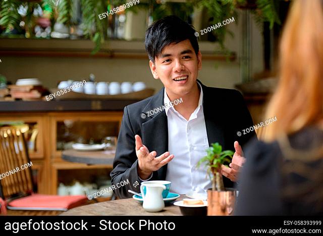 Portrait of young Asian businessman and young Asian businesswoman together relaxing at the coffee shop