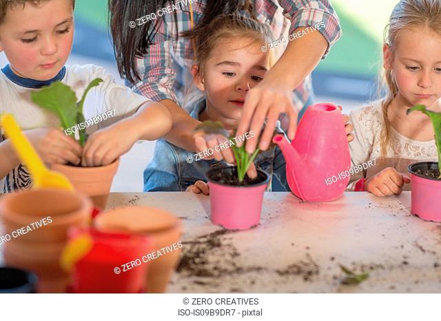Mid adult woman helping young children with gardening activity