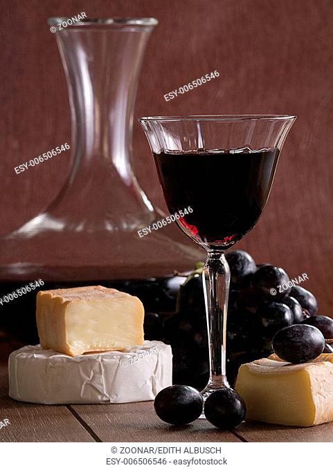 A glass of red wine with cheese and grapes