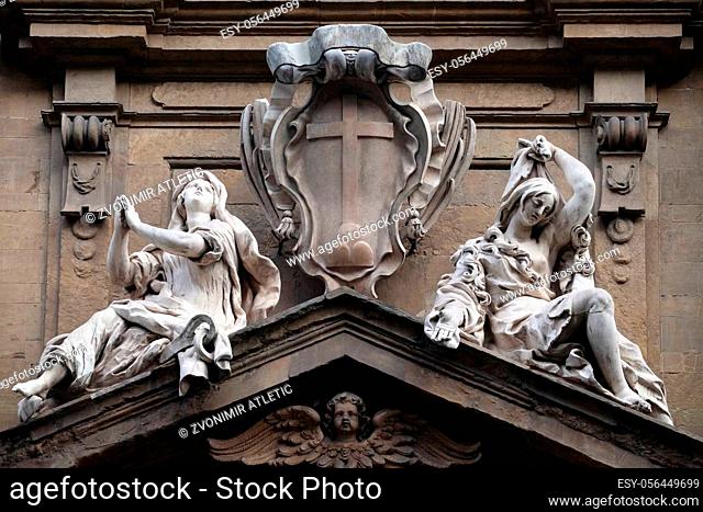 Statues of Hope and Poverty seated either side of the arms of the Theatine order over the central door on the facade of Santi Michele e Gaetano church in...