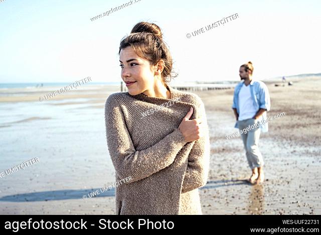 Girlfriend and boyfriend looking away while standing on beach during sunny day