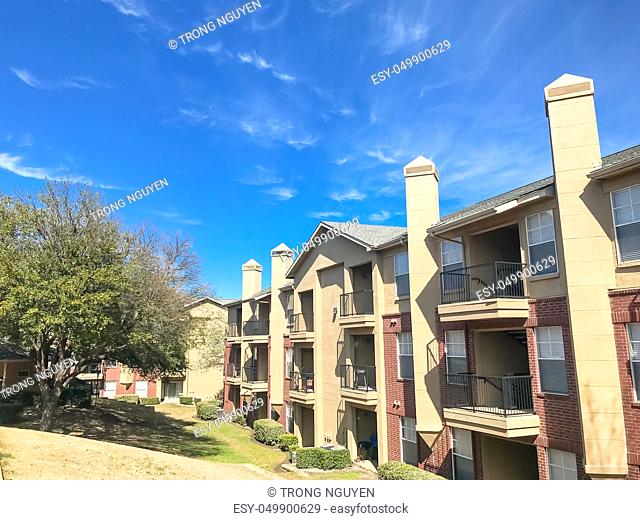 Typical apartment complex building with hillside backyard in Lewisville, Texas, USA. Sunny spring day with blue sky and white clouds over high chimney