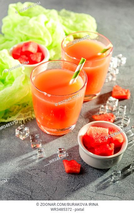 Watermelon drink with ice in glasses on gray concrete background