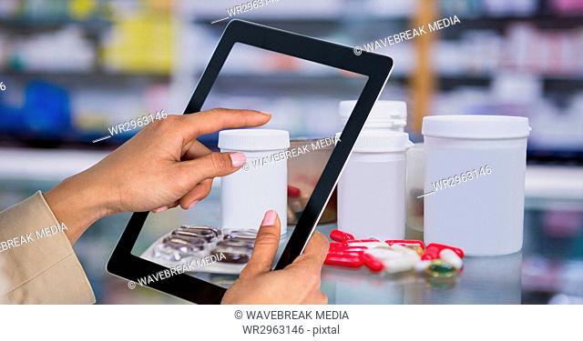 Hands taking picture of medicines with tablet PC in pharmacy