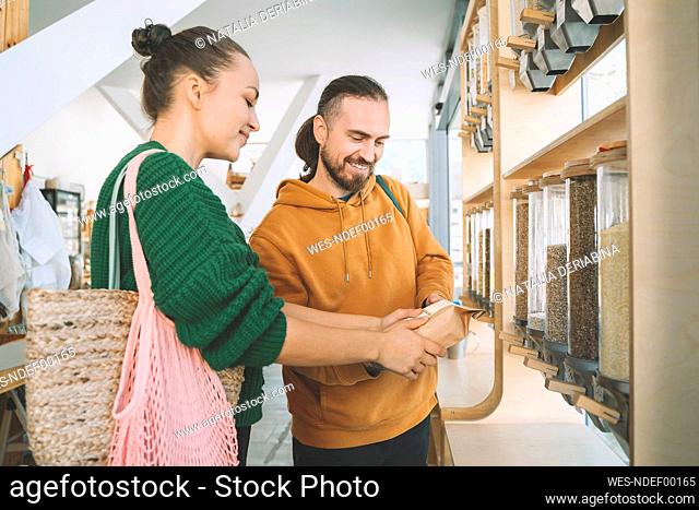 Smiling couple discussing over food package in zero waste store