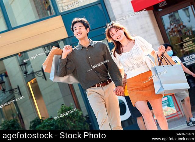 The happy couple hand in hand to go shopping shopping