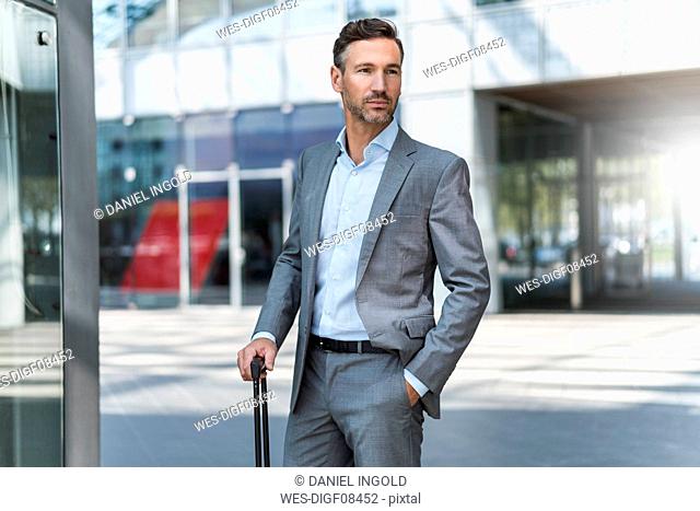 Portrait of confident businessman with baggage