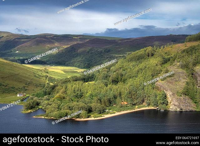 Beautiful aerial panorama with houses, lake, sandy beach, green forest and mountains. Lough Dan in Wicklow Mountains, Ireland