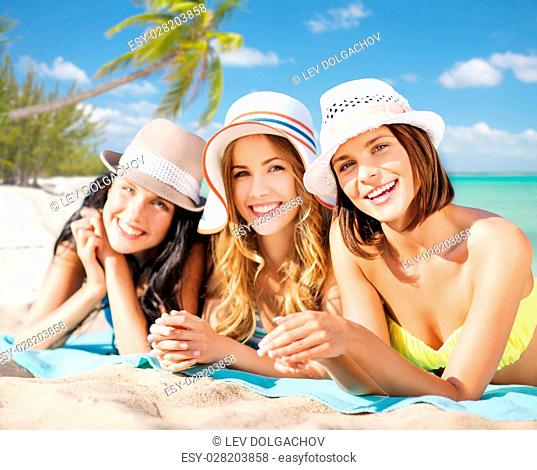 summer holidays, vacation, travel and people concept - group of smiling young women in hats lying over exotic tropical beach with palm trees background