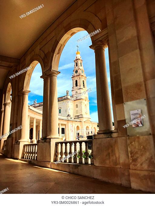 The bell tower of th Sanctuary of Our Lady of Rosary of Fatima seen between the arches of the sanctuary in Fatima, Portugal