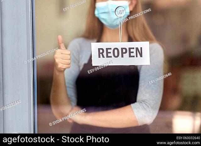 woman in mask with reopen banner showing thumbs up