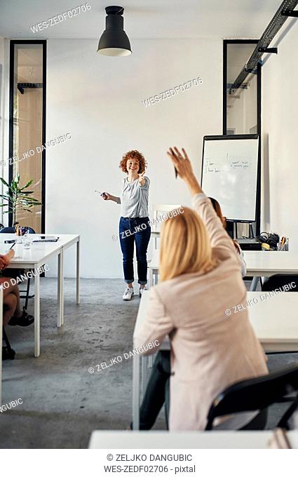 Businesswoman raising her hand during a workshop in conference room