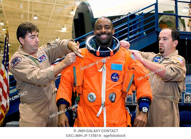 Astronaut Leland D. Melvin, STS-122 mission specialist, dons a training version of his shuttle launch and entry suit in preparation for a post insertionde-orbit...