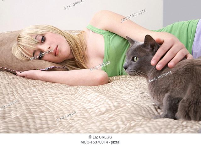 Teenage girl 16-17 lying on bed with cat