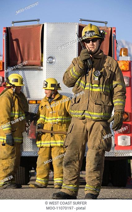 Firefighter using walkie talkie by fire engine