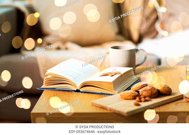 book with autumn leaf, cookies and tea on table