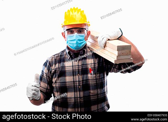 Carpenter worker isolated on white background wears surgical mask to prevent Coronavirus spread, makes OK sign with thumb up