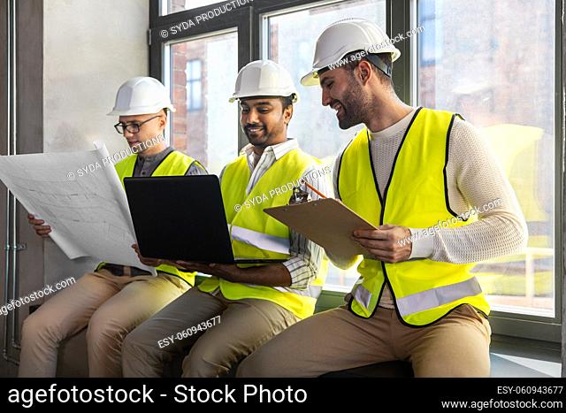 male architects in helmets with laptop at office