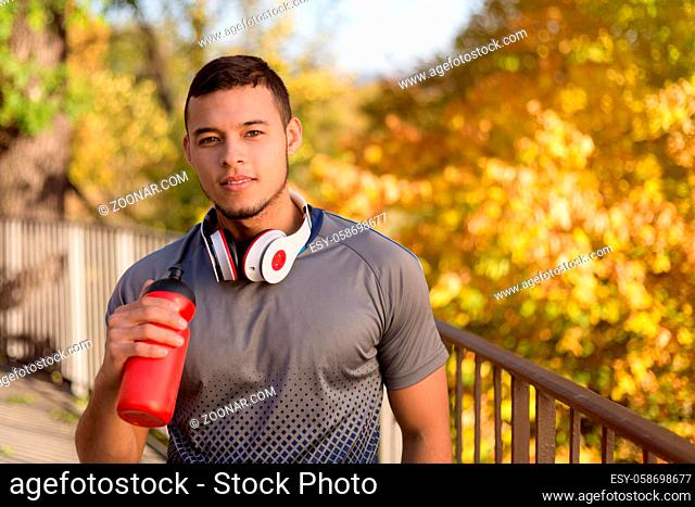Young latin man drinking water runner running jogging autumn fall copyspace copy space outdoor