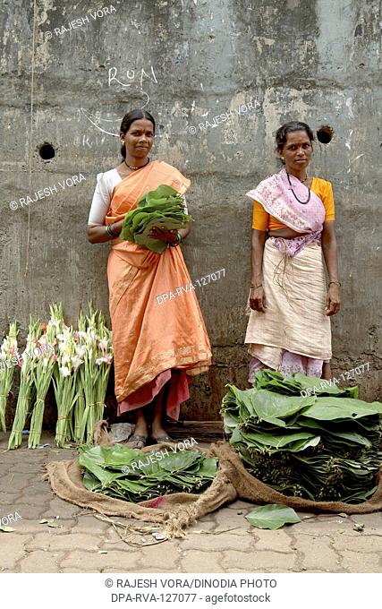 Women hawkers selling leaves to pack flowers for offering to Gods ;  Mumbai Bombay ; Maharashtra ; India