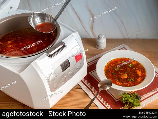 A delicious Ukrainian borscht is prepared for lunch in the multi-cooker. Next to it on a napkin is a plate of borscht