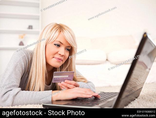 Beautiful relaxed woman relaxing on laptop lying on a carpet
