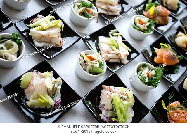 Fish entrée served on white plates and black dishes