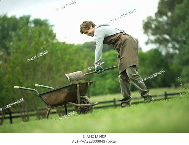 Man shoveling dirt into wheelbarrow