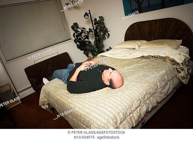 Middle-age balding man lying on his bed