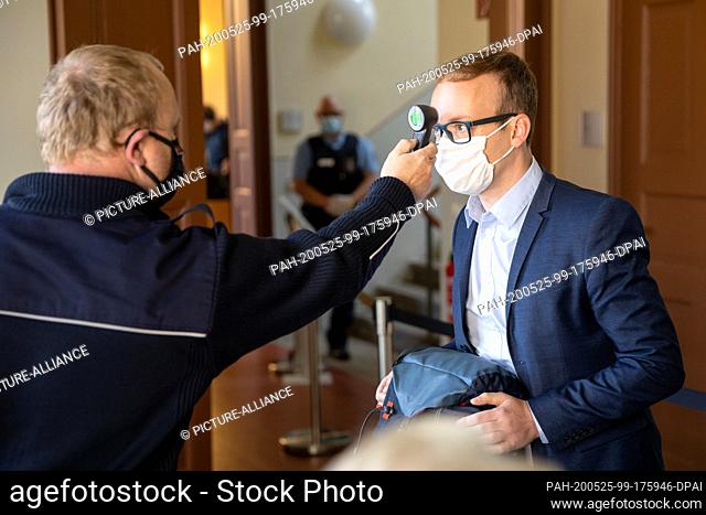 25 May 2020, Thuringia, Weimar: A security guard measures the temperature of a session participant at the Thuringian Constitutional Court before the hearing on...